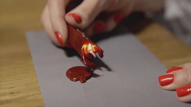 Girl put a seal with a sealing wax.Red wax seal or signet on lilac envelope.