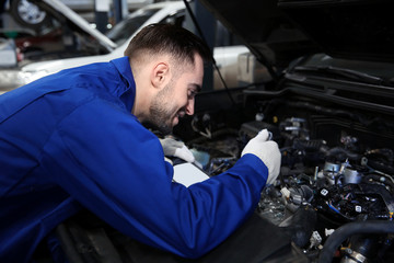 Mechanic repairing car with open hood