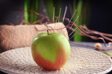 Apple with acupuncture needles on plate