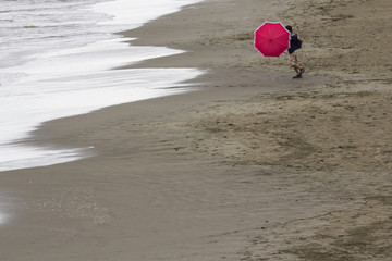Boy with umbrella on the beach, playing with the wind