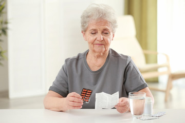 Elderly woman with pills and instruction at home