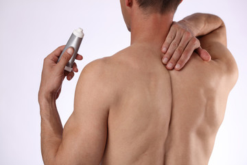 Man applying pain relieving cream, gel. Sport injury, Man with back, neck pain. Pain relief and health care concept.