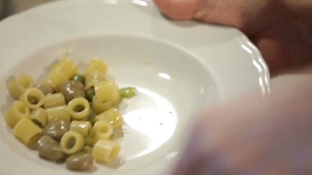 donna impiatta pasta e fave in un piatto bianco in una cucina di casa italiana