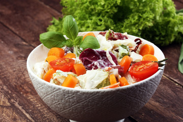 bowl of salad with vegetables and greens on wooden table