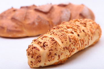 Assorted fresh breads, slice and knife isolated on old wood table.