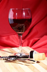 Wine corks, corkscrew and Glass with red wine grapes on wooden table.