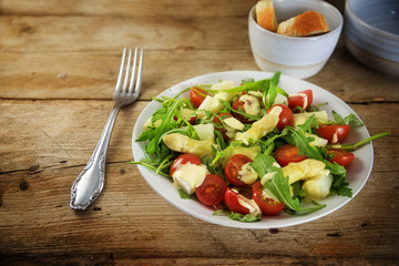 salad from white asparagus, cocktail tomatoes and arugula on a rustic wooden table