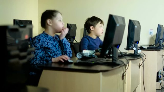 Young, male teacher helping his students build a robot 4k