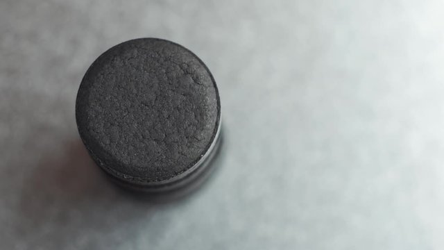 Closed up Activated charcoal carbon pills turning on a metal background, top view.