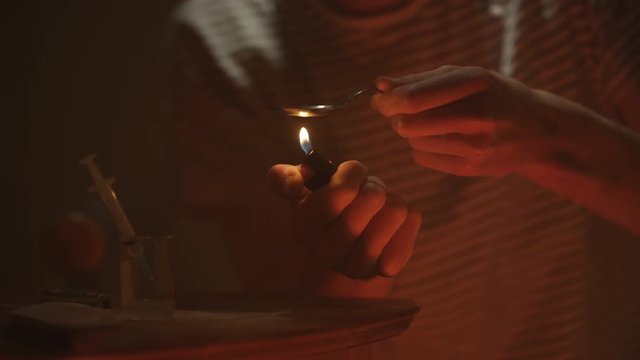  Drug addict in gloomy apartment preparing & injecting heroin into arm