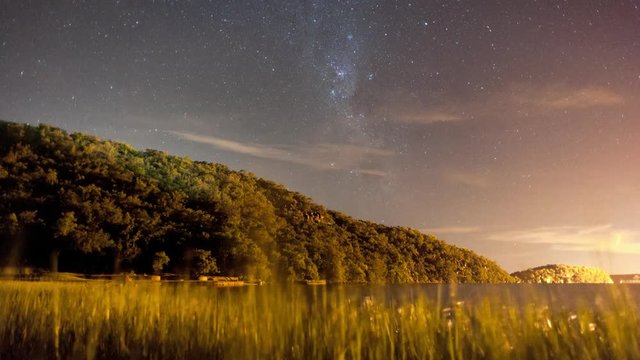 Linear and pan timelapse at night time of a mountain at a dam with the Milky Way rising and a few scattered clouds moving through available on request.