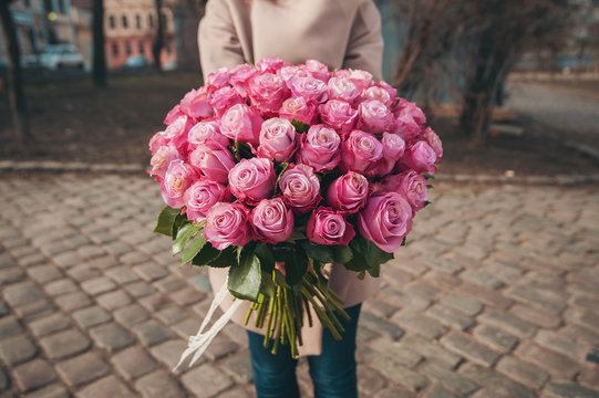 Big bouquet of pink roses in the girl's hands. A gift on birthday, a card, a background