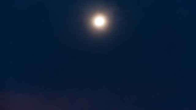 Static night timelapse of the moon rising during the blue hour until the sky goes dark with a few scattered clouds in the foreground available on request.