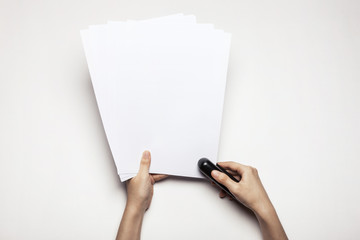 woman(female) hand hold a stapler with paper isolated white.