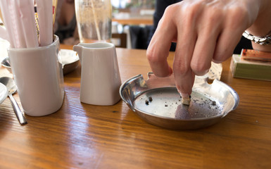 Hand putting out a cigarette in ashtray