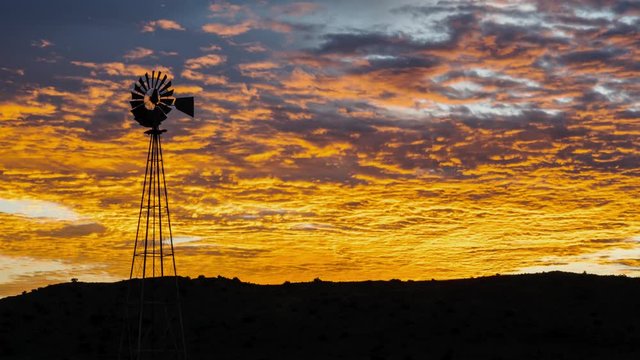 Static sunrise timelapse with a dramatic orange and yellow glow and scattered clouds with a silhouetted windmill in the foreground available on request.