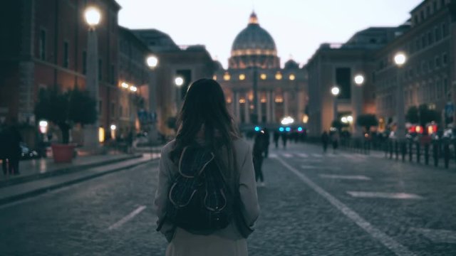 Young tourist woman walking in Piazza di spagna near the Saint Peter Cathedral. Girl looking around, exploring sights.