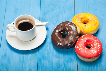 Cup with coffee and donuts on a blue wooden table