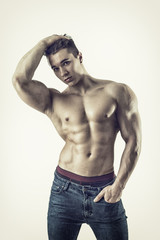 Obraz premium Handsome young muscular man shirtless wearing jeans, on lightbackground in studio shot