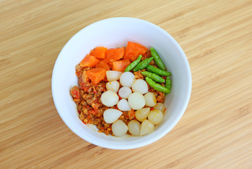 Nam prik ong and Spicy meat and vegetable on white plate against bamboo wooden board