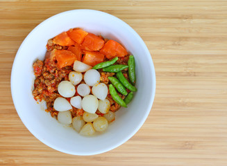 Nam prik ong and Spicy meat and vegetable on white plate against bamboo wooden board