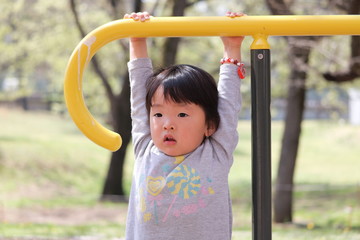 Fototapeta premium 遊具にぶら下がる女の子