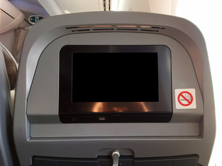 Passenger seat of plane with blank empty black monitor screen, and no smoking allowed sign