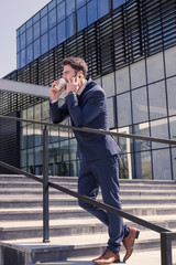 one young man, suit tie, talking over phone, outdoors day, modern building