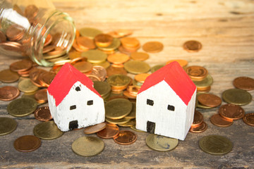 Miniature house and coins on wooden table