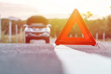 Red emergency stop sign and broken silver car on the road
