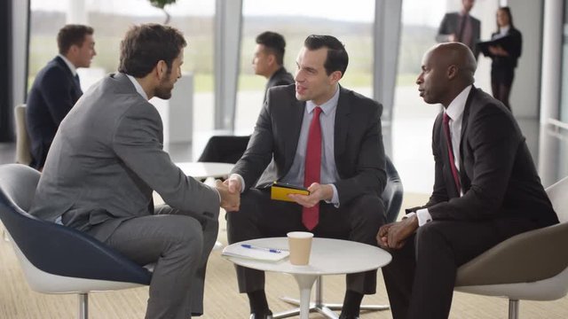  Male corporate business team in negotiation in busy modern office