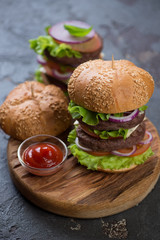 Hamburgers with white sesame buns, double beef cutlets and vegetables, vertical shot