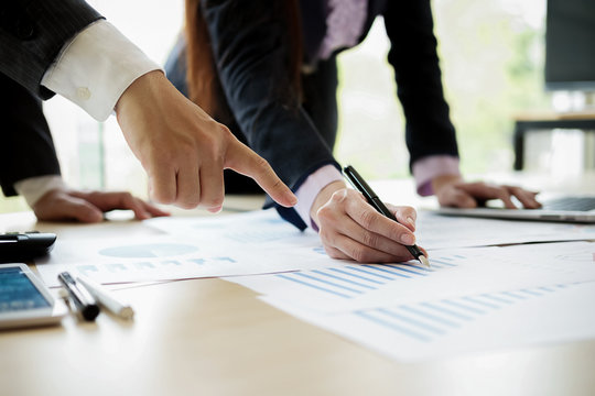 Business concept. Business people discussing the charts and graphs showing the results of their successful teamwork. Selective focus.