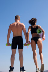 Attractive fitness couple posing on sky background. 