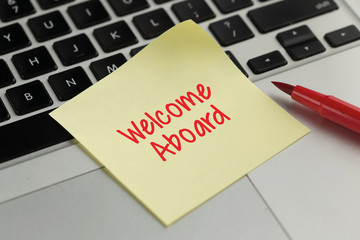 Welcome Aboard sticky note pasted on the keyboard