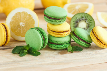 Green and yellow french macarons with kiwi, lemon and mint decorations