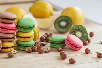 Green, pink, yellow and brown french macarons with lemon, kiwi and hazelnuts