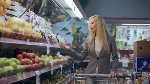 Beautiful young woman with trolley shopping in supermarket