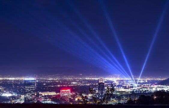 Huge spotlight rays over the night panorama of Los Angeles city