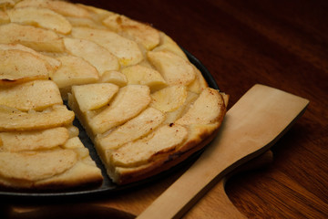 Homemade apple pie, and piece of pie with apple slices on cook board.
