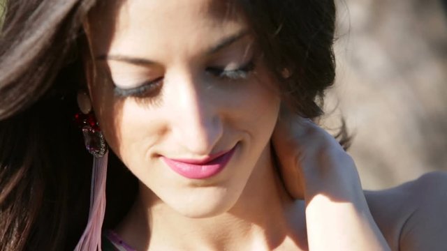 Ragazza con orecchini rosa che si tocca i capelli al vento