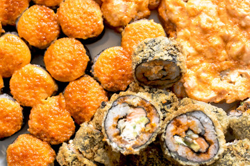 Sushi rolls with salmon, black caviar and sesame close-up macro shot