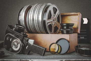 Naklejka premium Reels with films in a wooden box, lens and an old movie camera