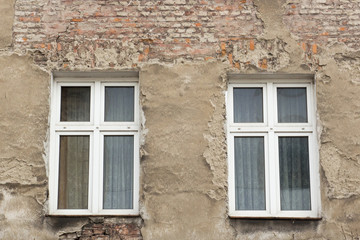 Fototapeta na wymiar Six windows on the facade of the ragged old house