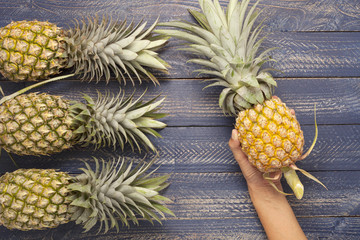 Row of pineapple fruits on wooden table background.