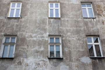 Fototapeta na wymiar Windows on the facade of the ragged old gray house
