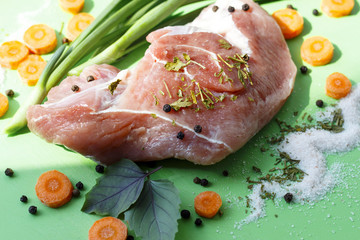 raw piece of meat with spices, with herbs and carrots closeup