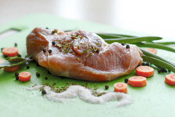 raw piece of meat with spices, with herbs and carrots closeup