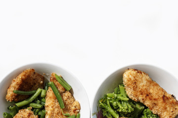 chicken in breadcrumbs with green beans and broccoli in a white plate