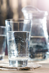 Glass of water against the background of a decanter. With light effects. Selective focus. Shallow DOF. 